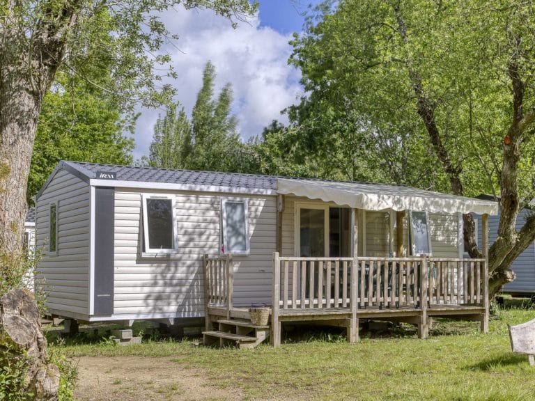 Mobil-home avec terrasse bois, ambiance verdoyante.